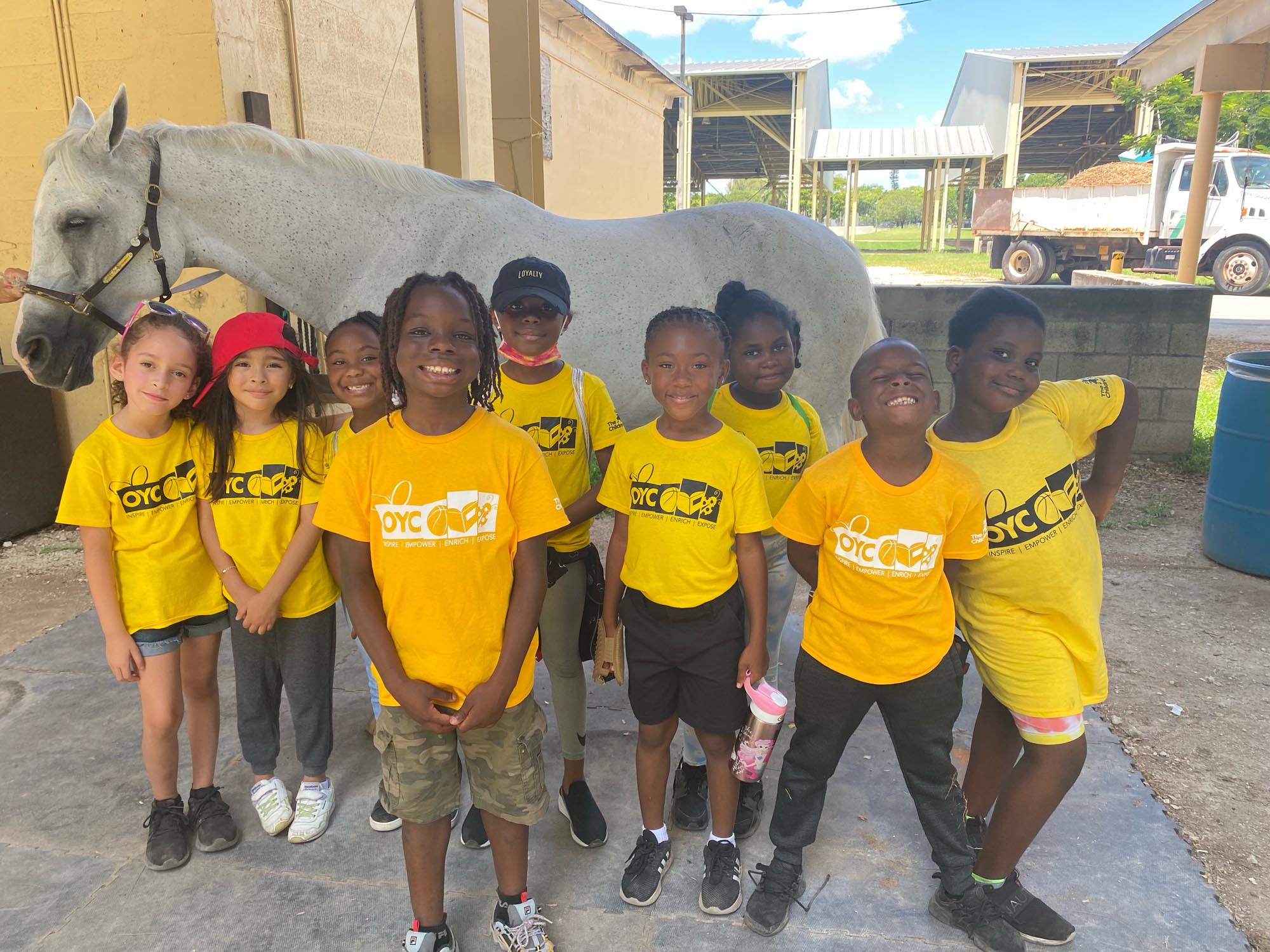 OYC Summer Camp attendees stand in front of a horse