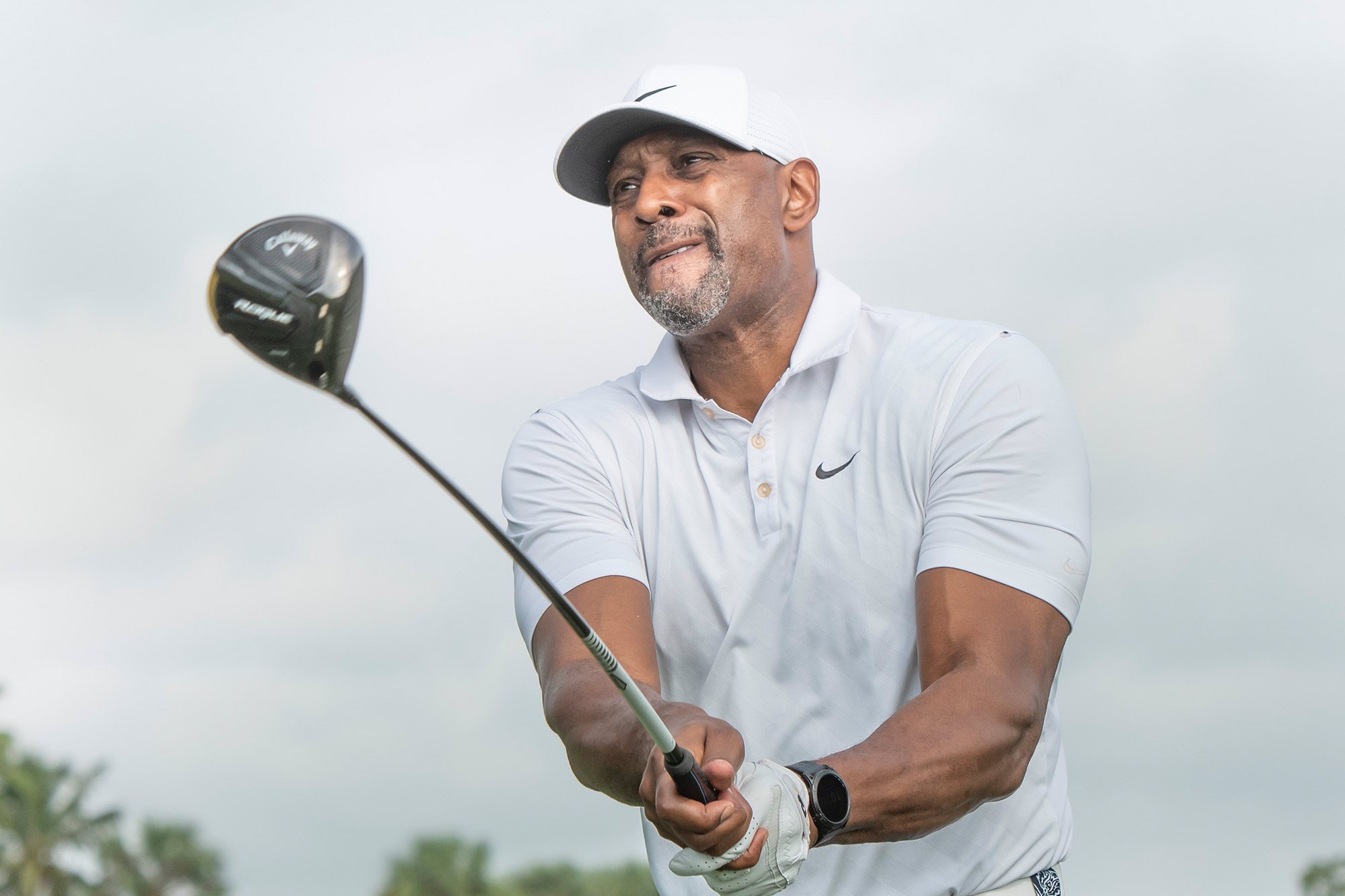 Alonzo Mourning holds a golf club steady after teeing off