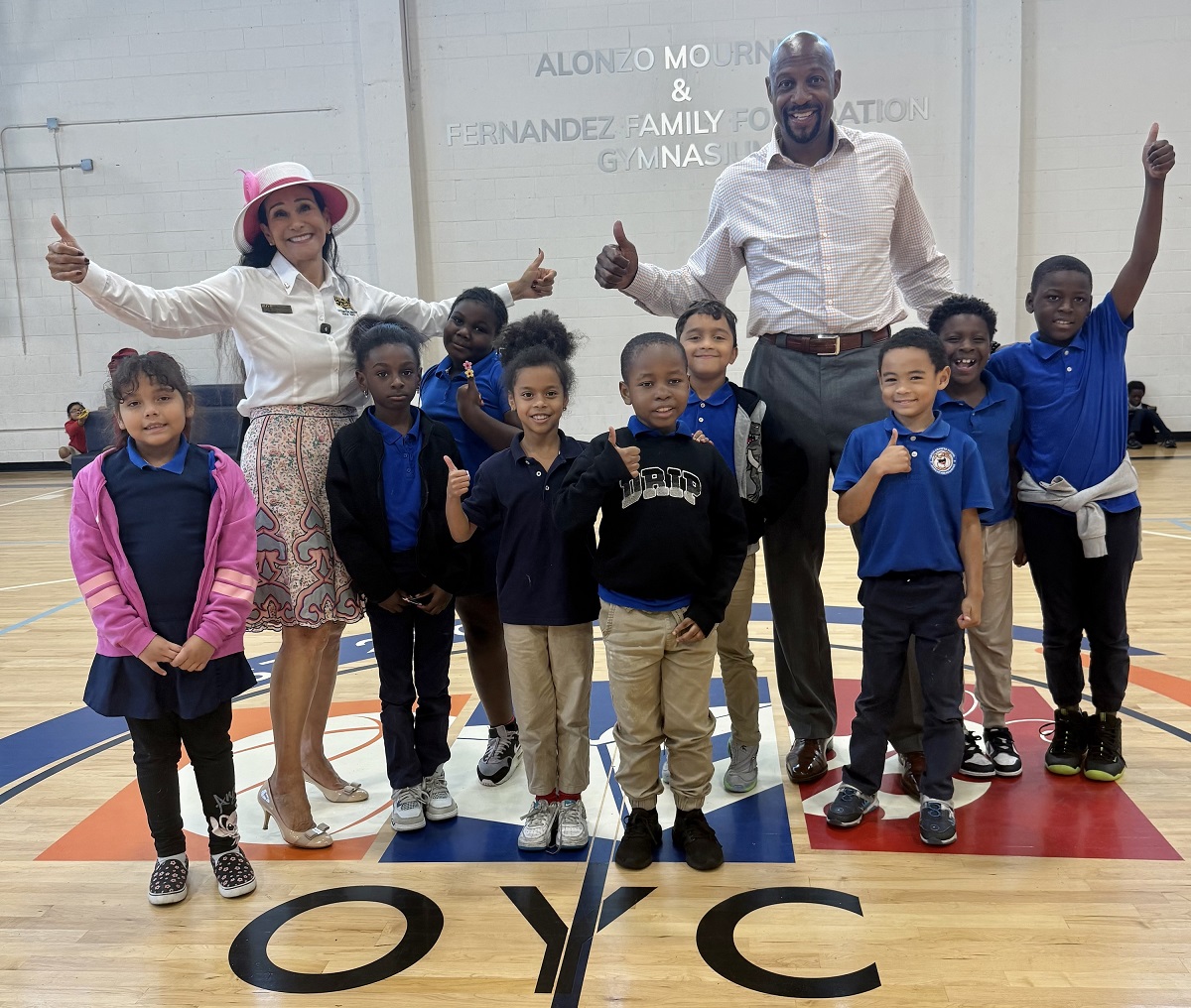 Rita Case, President and CEO of Rick Case Automotive Group, and Alonzo Mourning, NBA Hall-of-Famer and co-founder of Overtown Youth Center celebrate the truck donation with children who attend the center