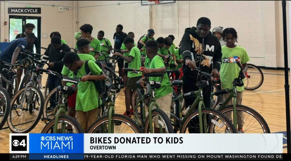 a group of children in a gymnasium receives new bicycles