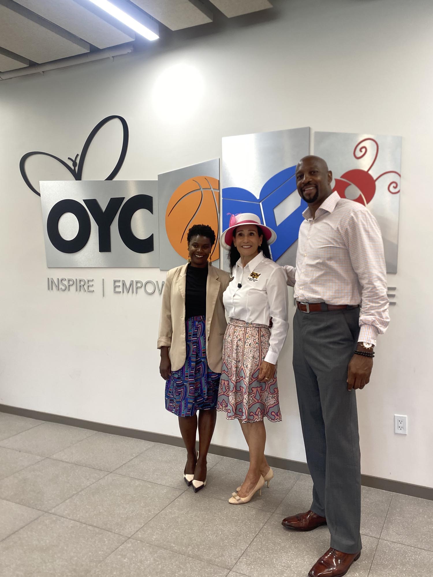 Tina Brown, Rita Case and Alonzo Mourning stand in front of an OYC Miami sign on a wall
