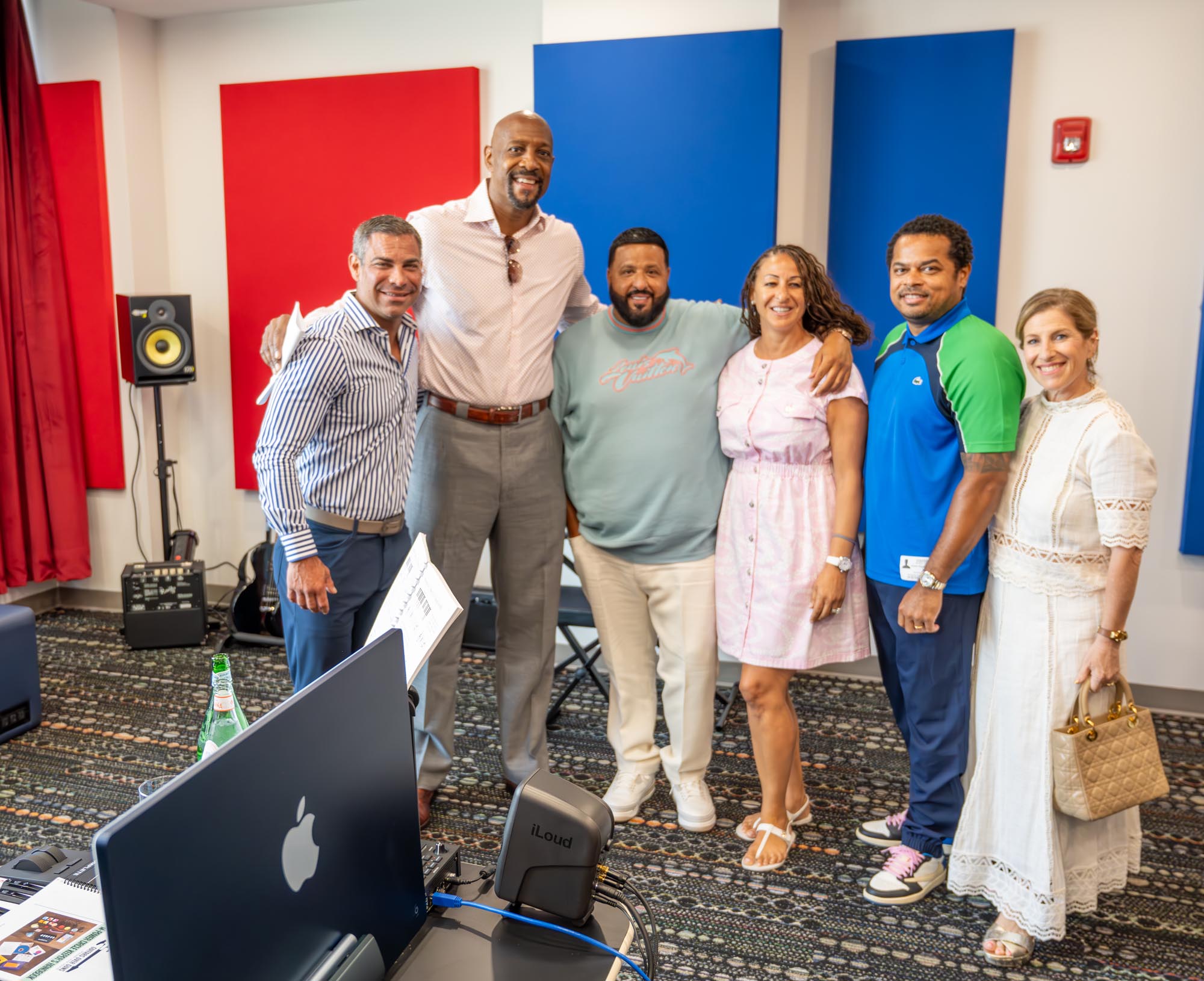 a group of people stand arm in arm for a photo in a recording studio room