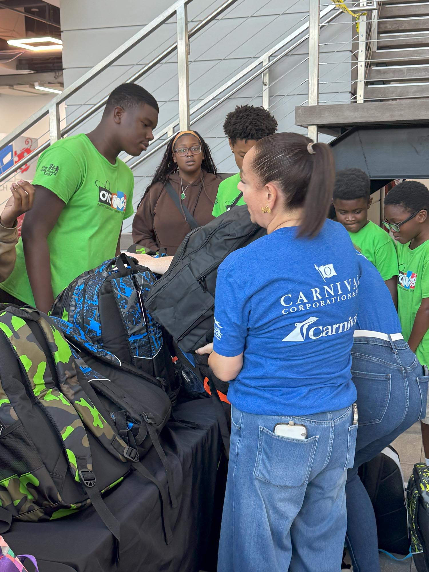 a volunteer distributes free backpacks to children