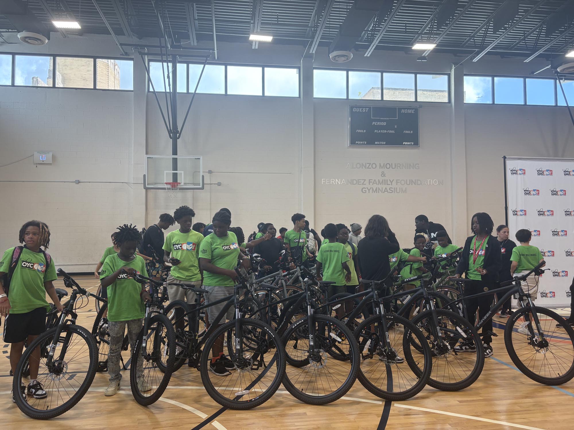a group of young children receive bicycles in a gymnasium