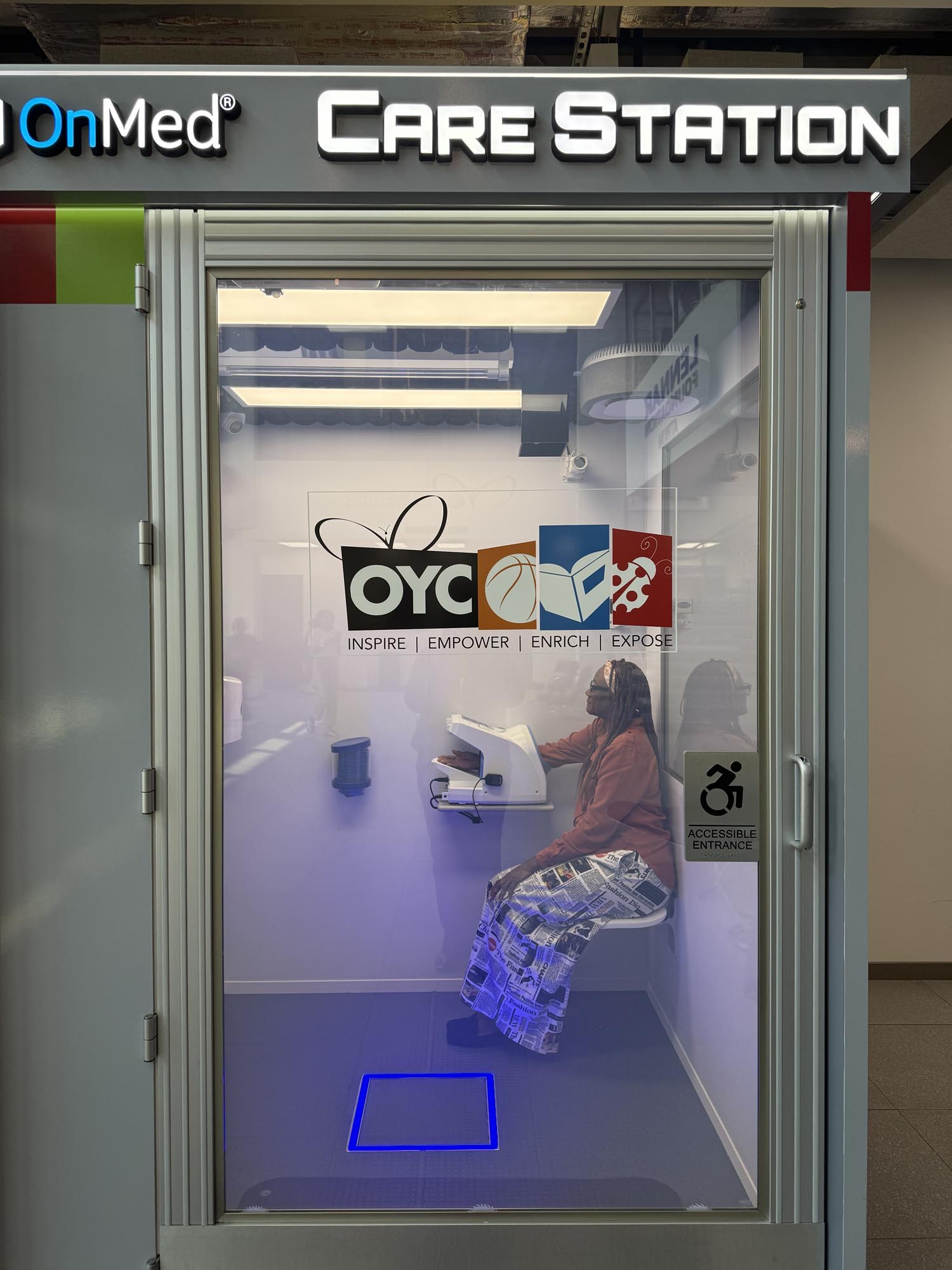 a woman gets her blood pressure checked inside an OnMed health kiosk at OYC Miami