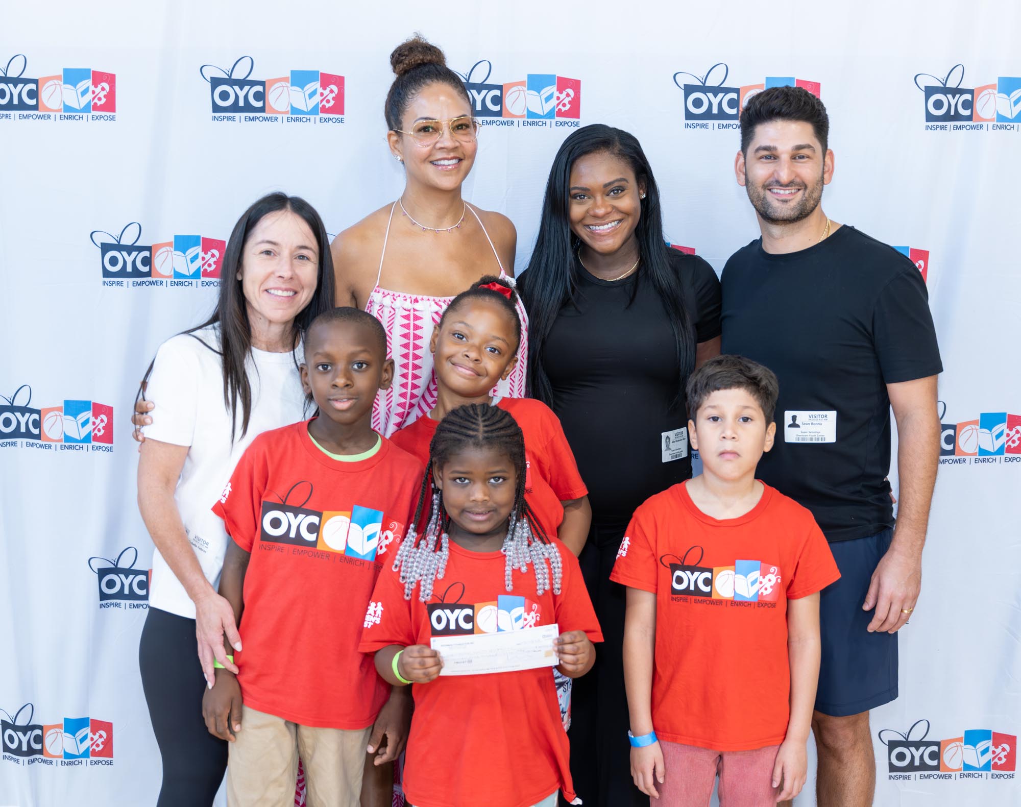 a group of children and adults in front of a step and repeat display