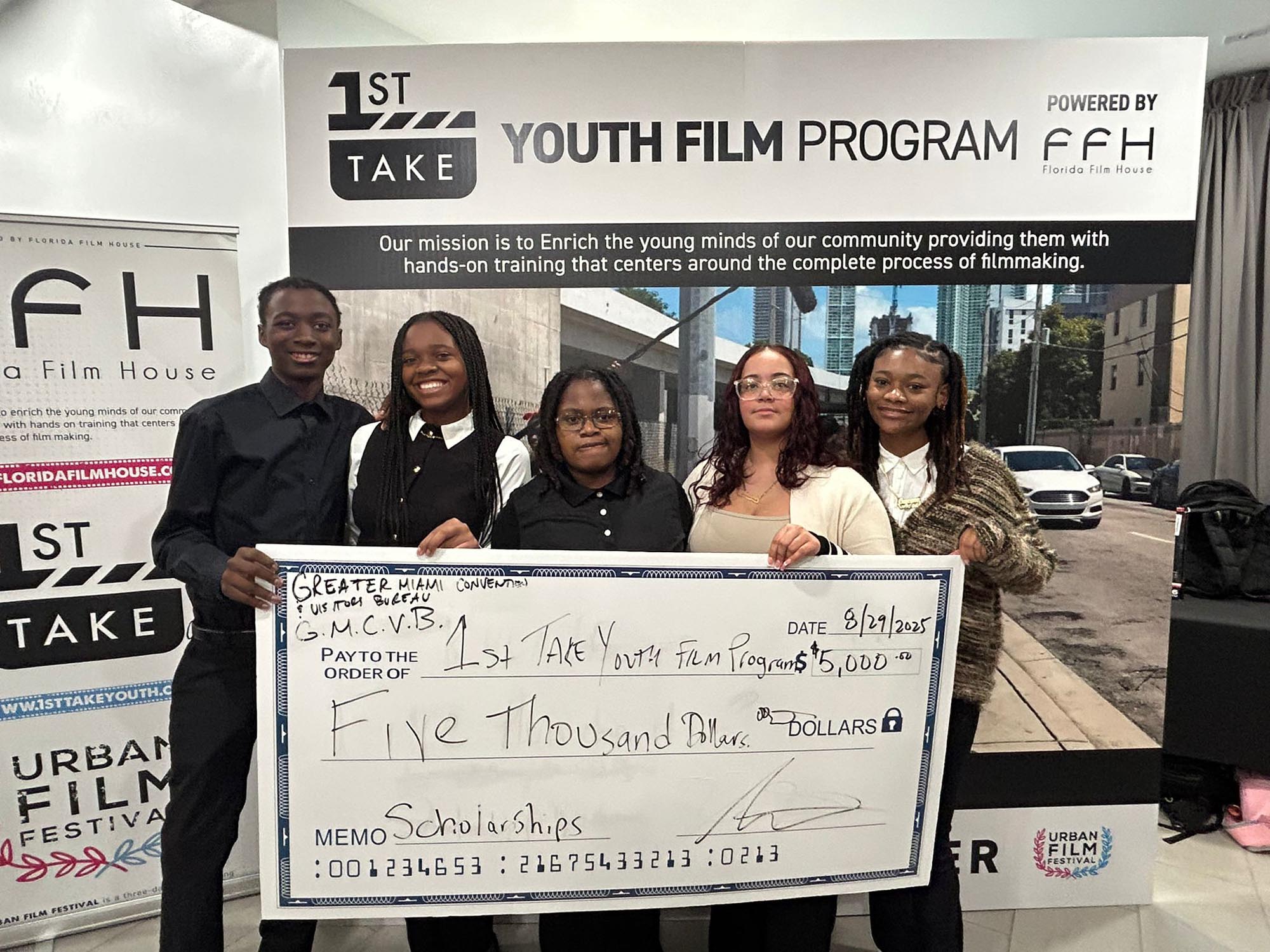 team members display a ceremonial check for a donation of $5000