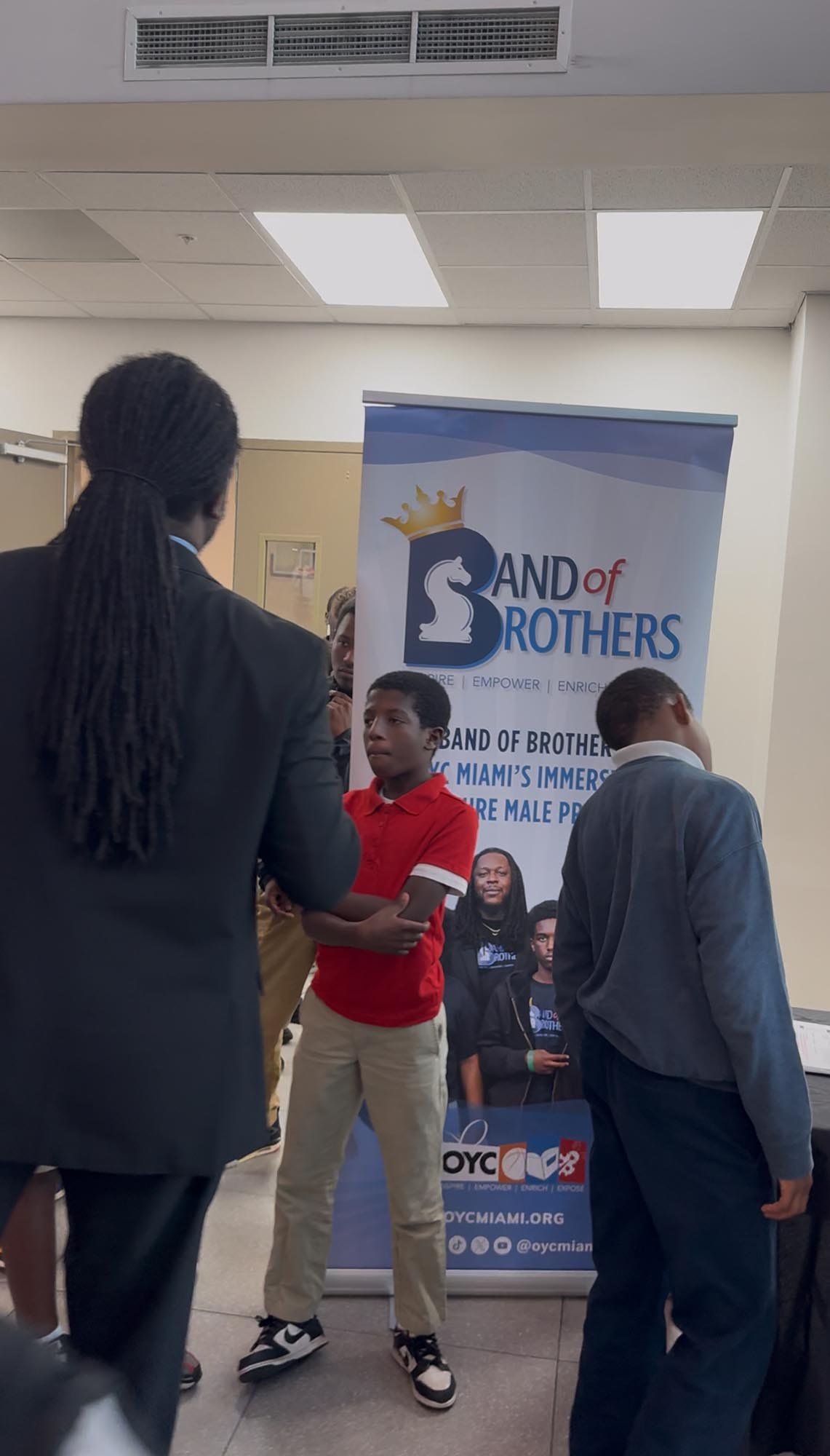 a young teenager interacts with an older male while standing in front of a banner