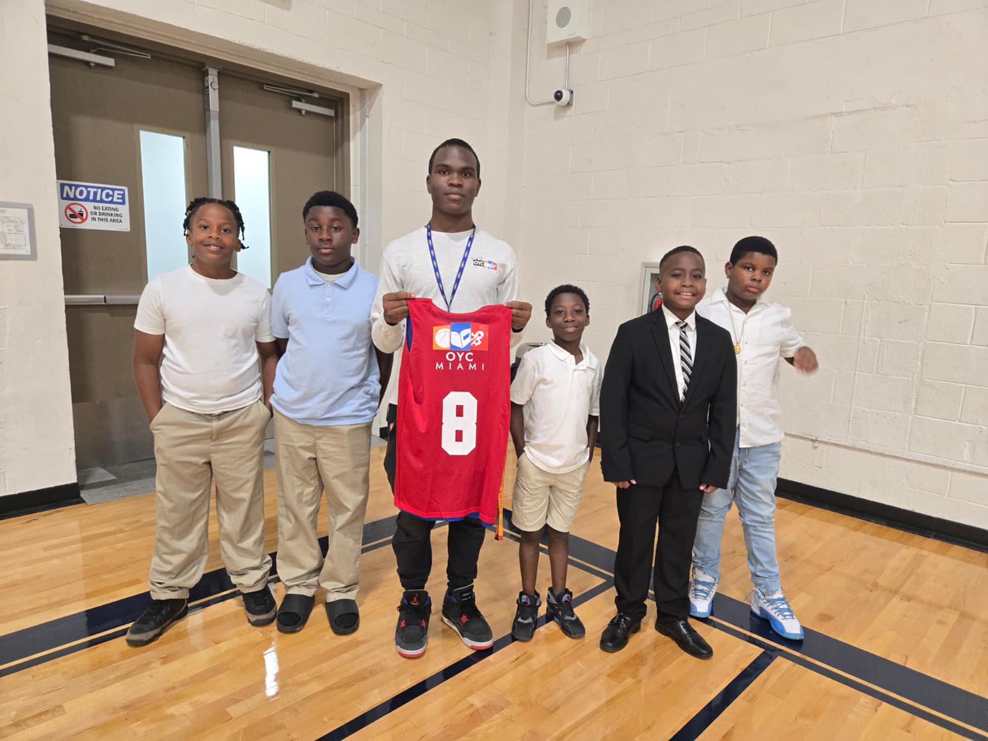 6 young men on a basketball court smile for a photo