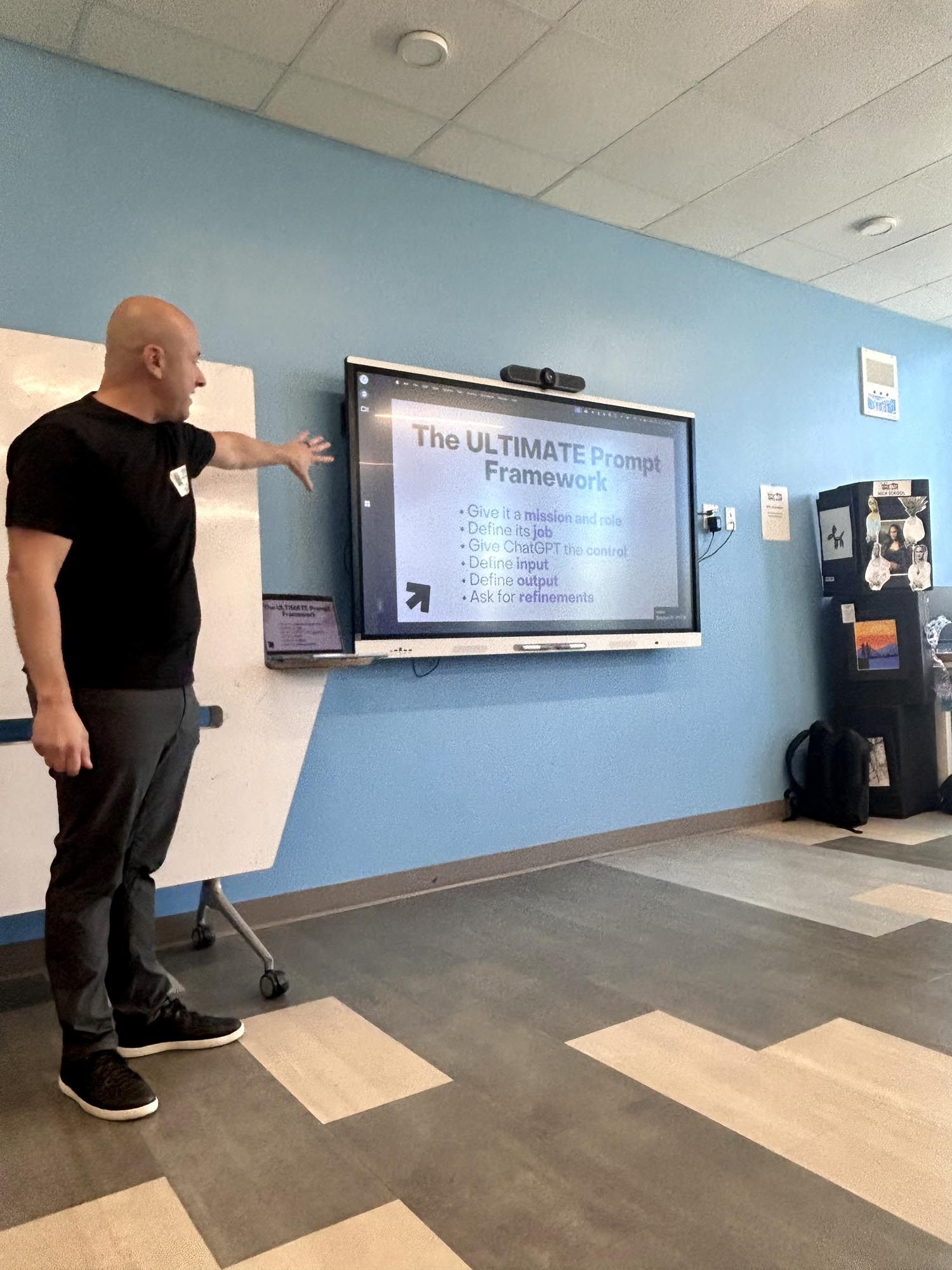 an instructor stands next to a large video screen in a room