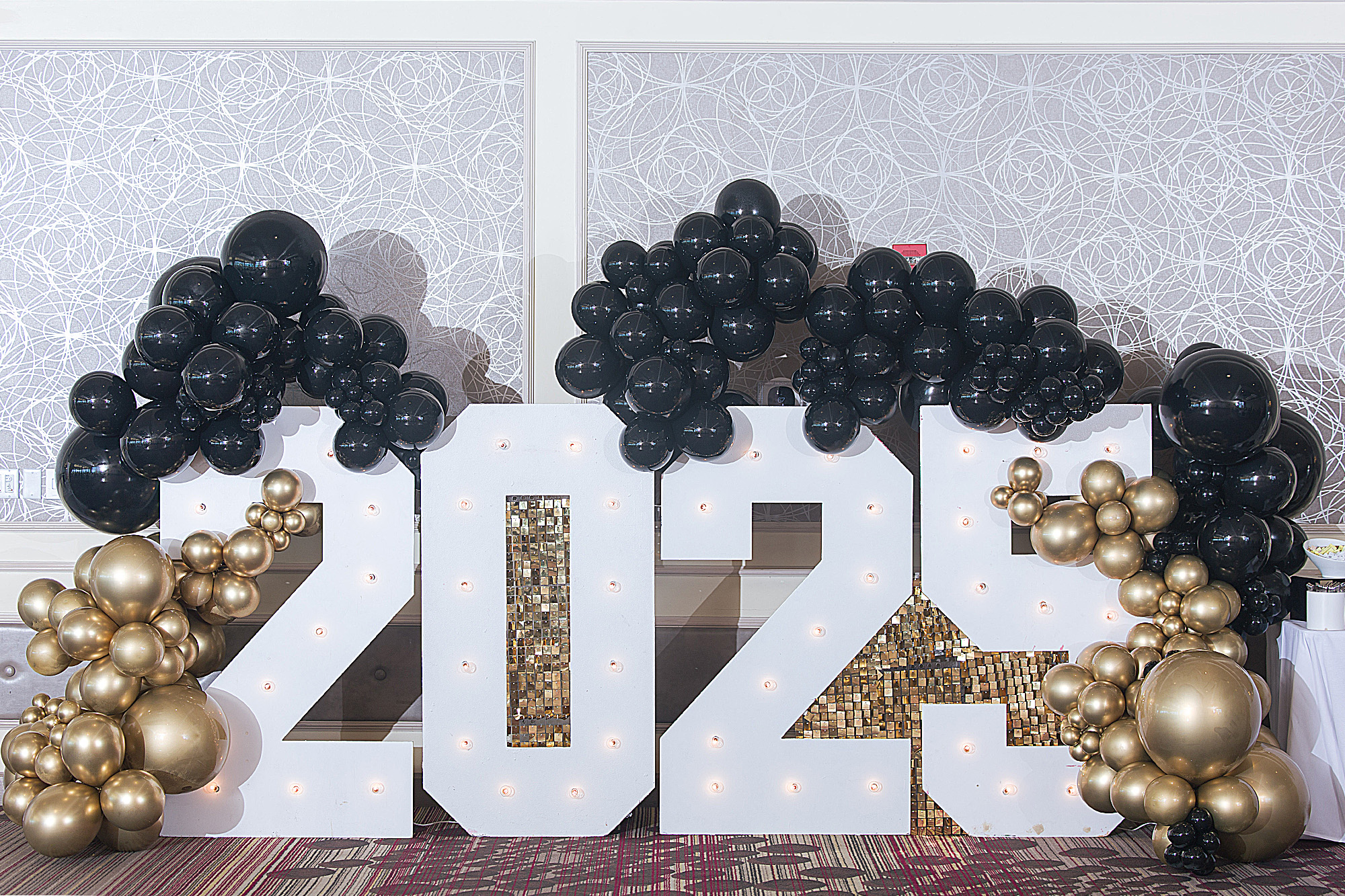 Black and gold balloons surround a large 2025 sign