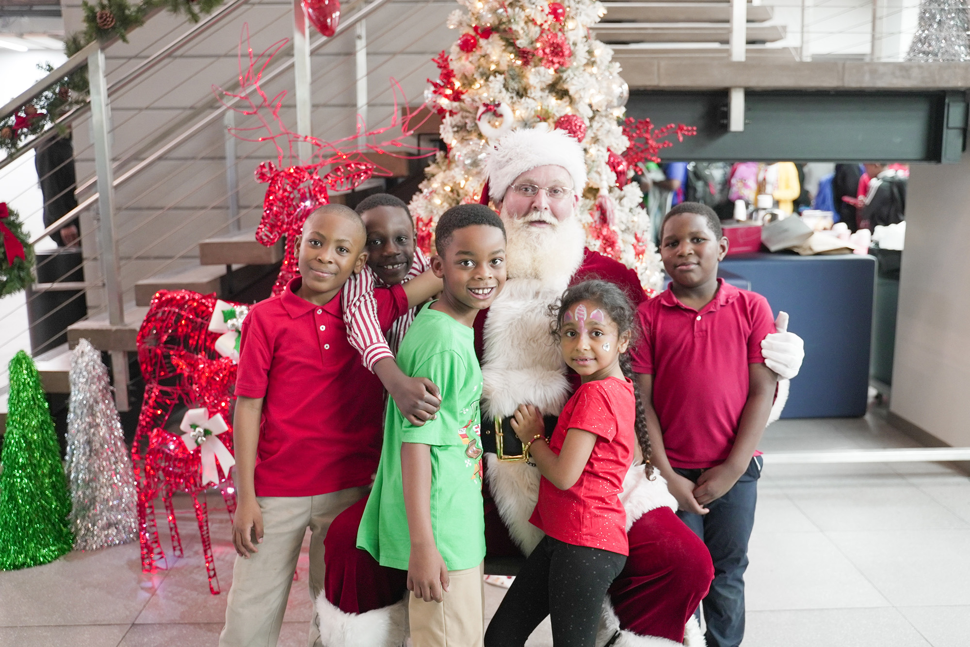 five children stand next to Santa and a Christmas tree