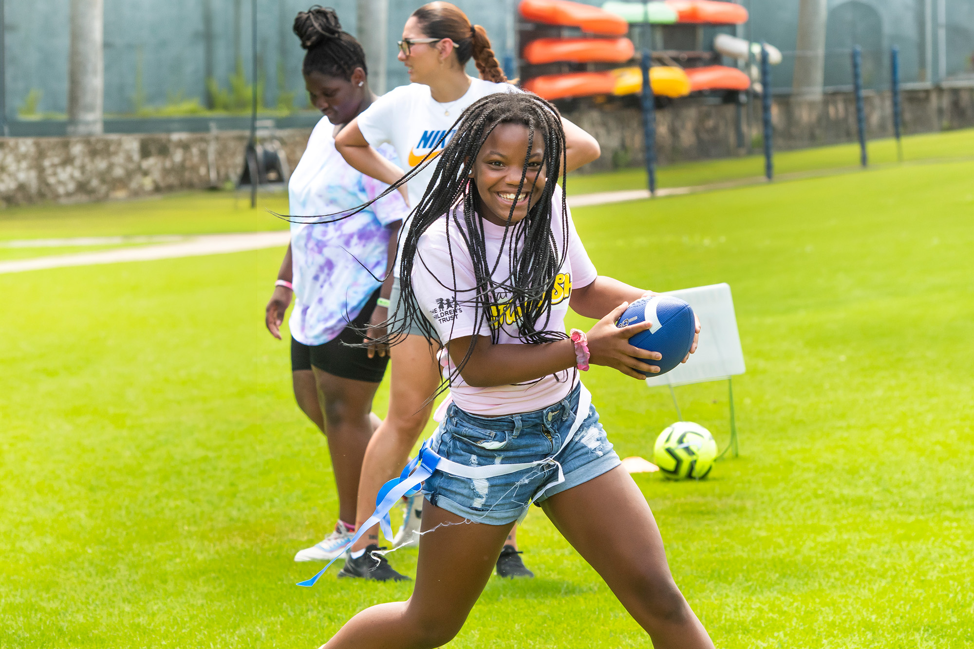 a girl runs with the ball as she plays flag football