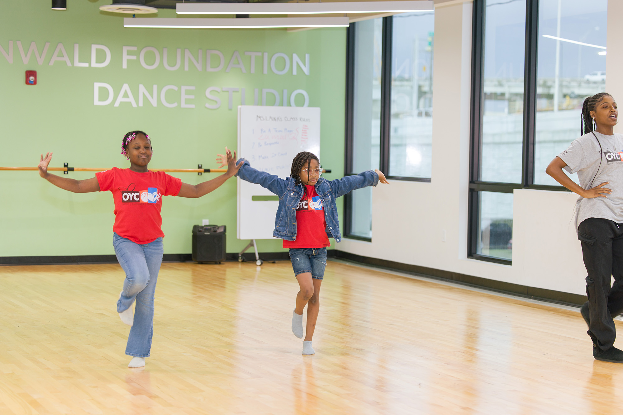 two girls and an instructor practice a dance routine in a studio