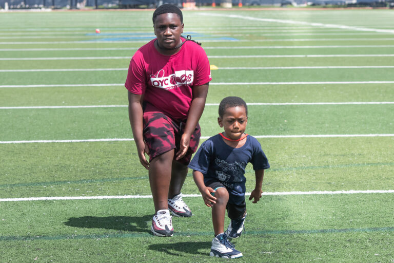 a very young boy gets ready to run. An older boy gets ready just behind him