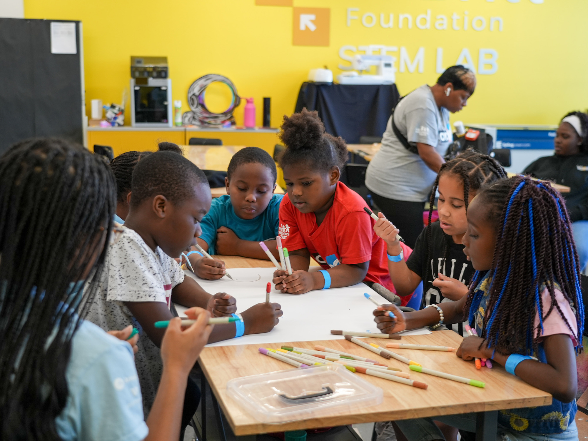 children around a table participate in arts and crafts