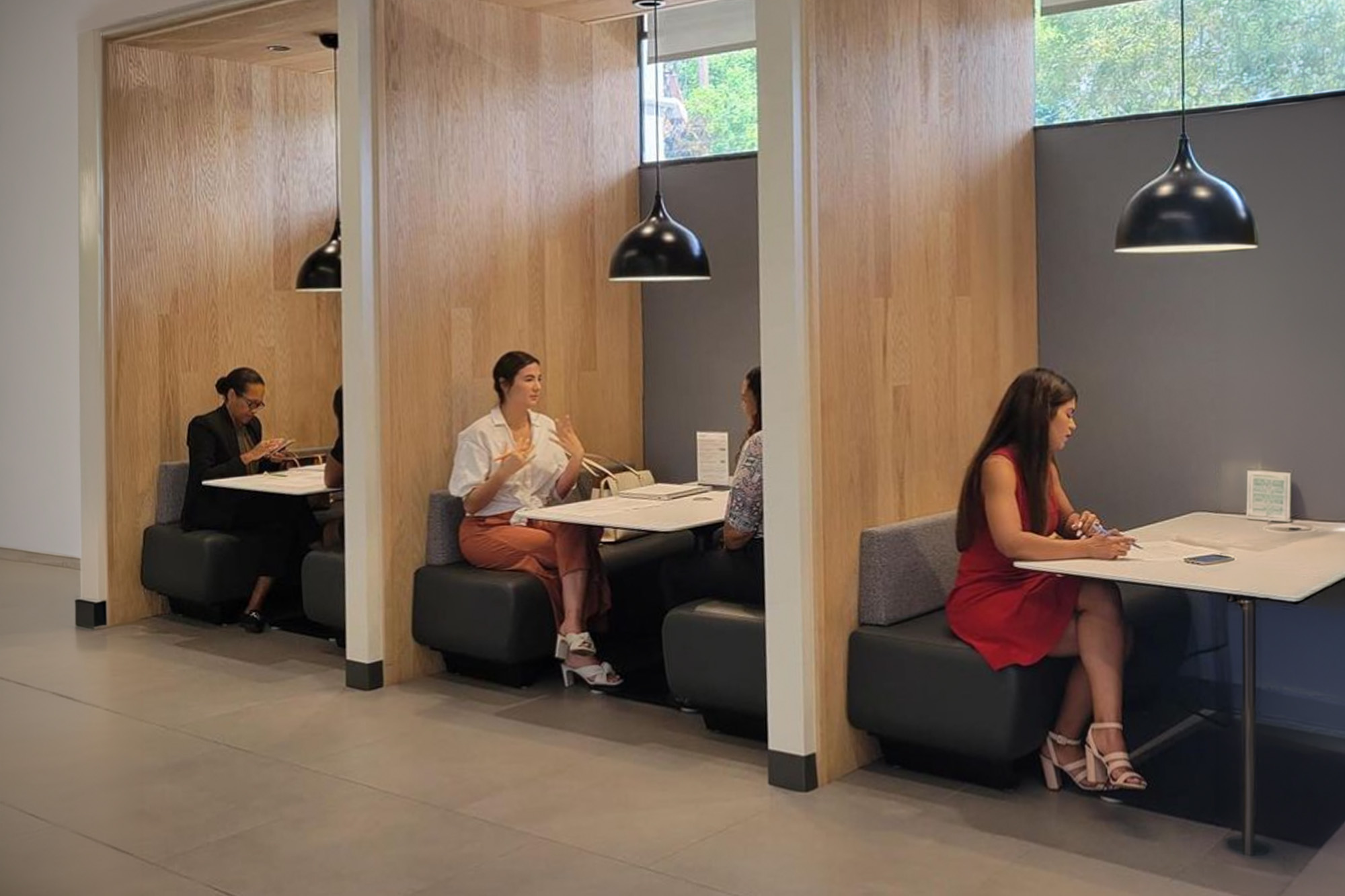 people seated at booths in a work lounge