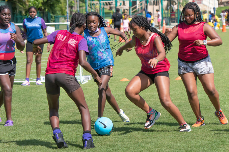 teen girls playing soccer on a field