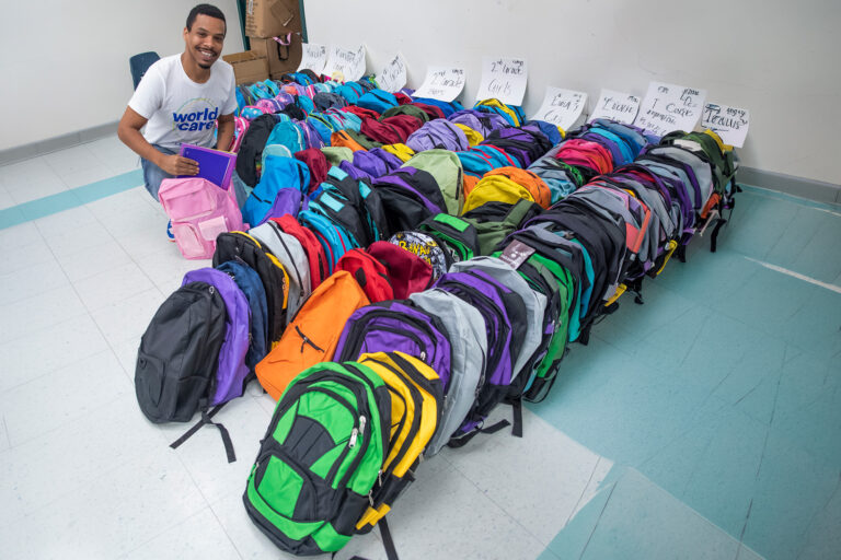 man in a room with rows of new backpacks ready to be distributed