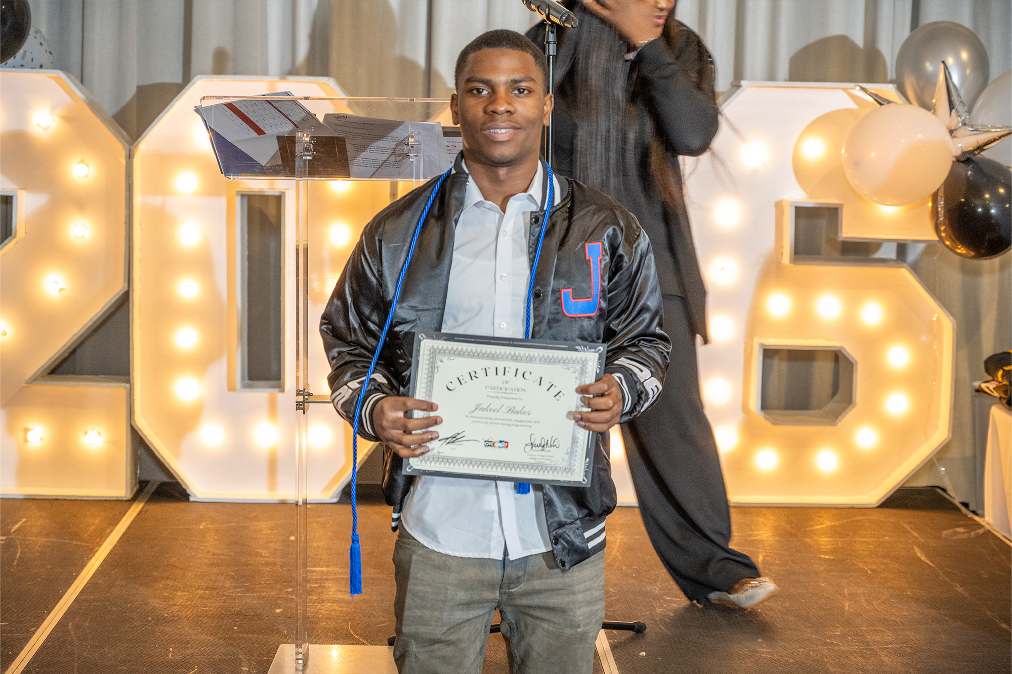 A young man proudly displays a certificate of completion